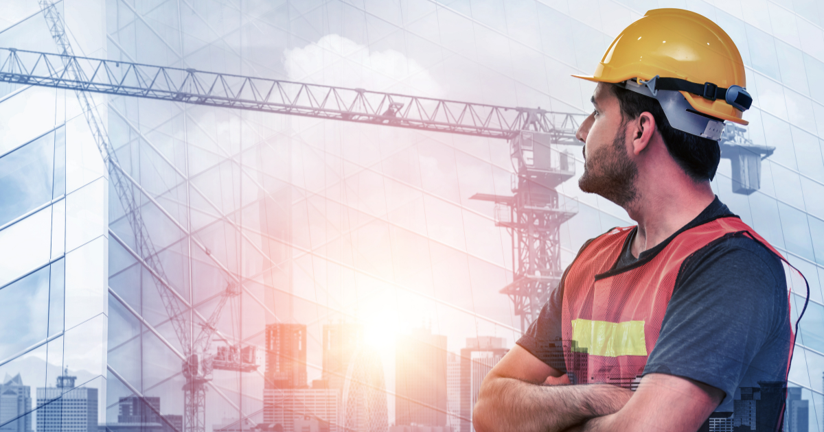 Construction worker looking into the horizon with tower cranes and buildings in the background